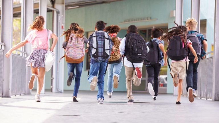 Group of elementary school kids running at school, back view