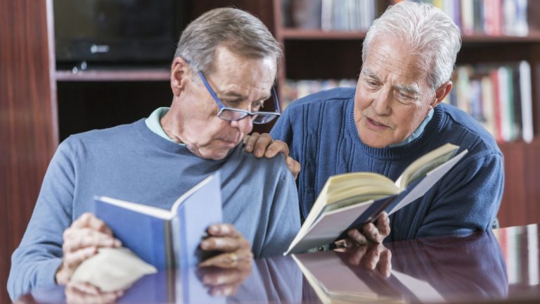 Two senior men reading books, talking