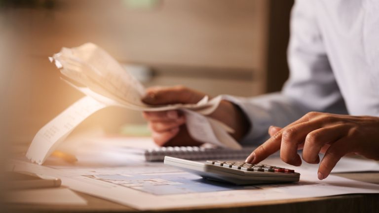 Close-up of business accountant using calculator while working i